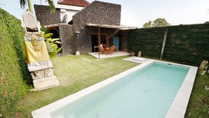 Piscina com parede de pedra e área de terraço coberta.