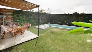 Um quintal com piscina, área de estar coberta e muro de pedra.