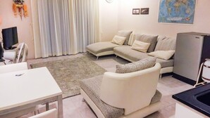 Ein modernes Wohnzimmer mit einer Sofagarnitur, einem Esstisch und einer Küchenzeile.