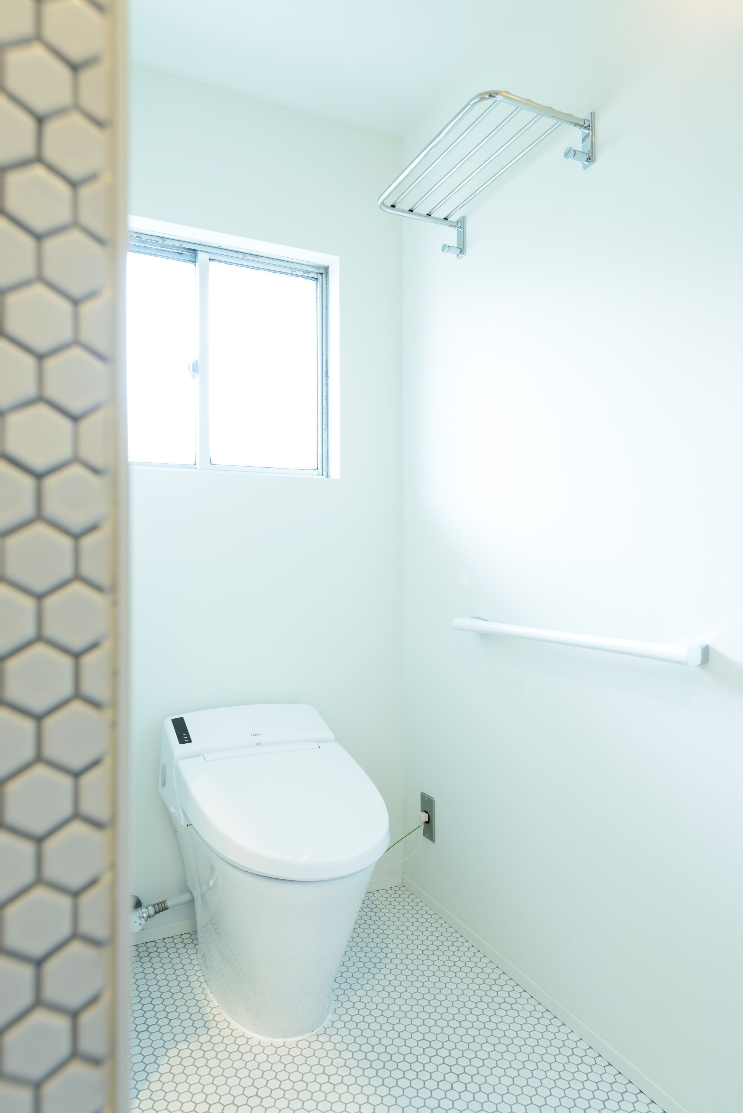 A bathroom with a toilet, a window, and a shower area.
