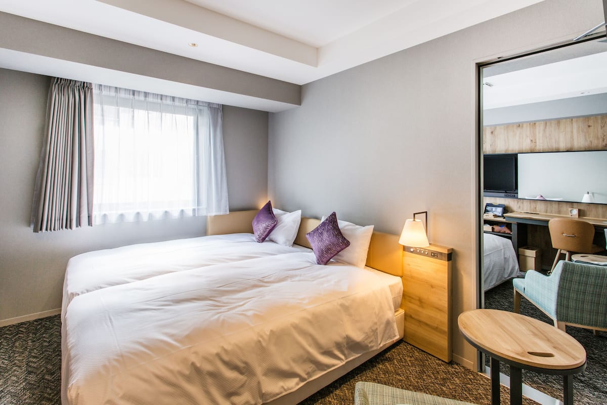 Une chambre d’hôtel avec un grand lit, un bureau, une chaise et une petite table.
