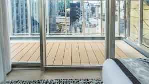 Ein modernes Hotelzimmer mit großem Balkon, einem Bett und Blick auf die Stadtlandschaft.