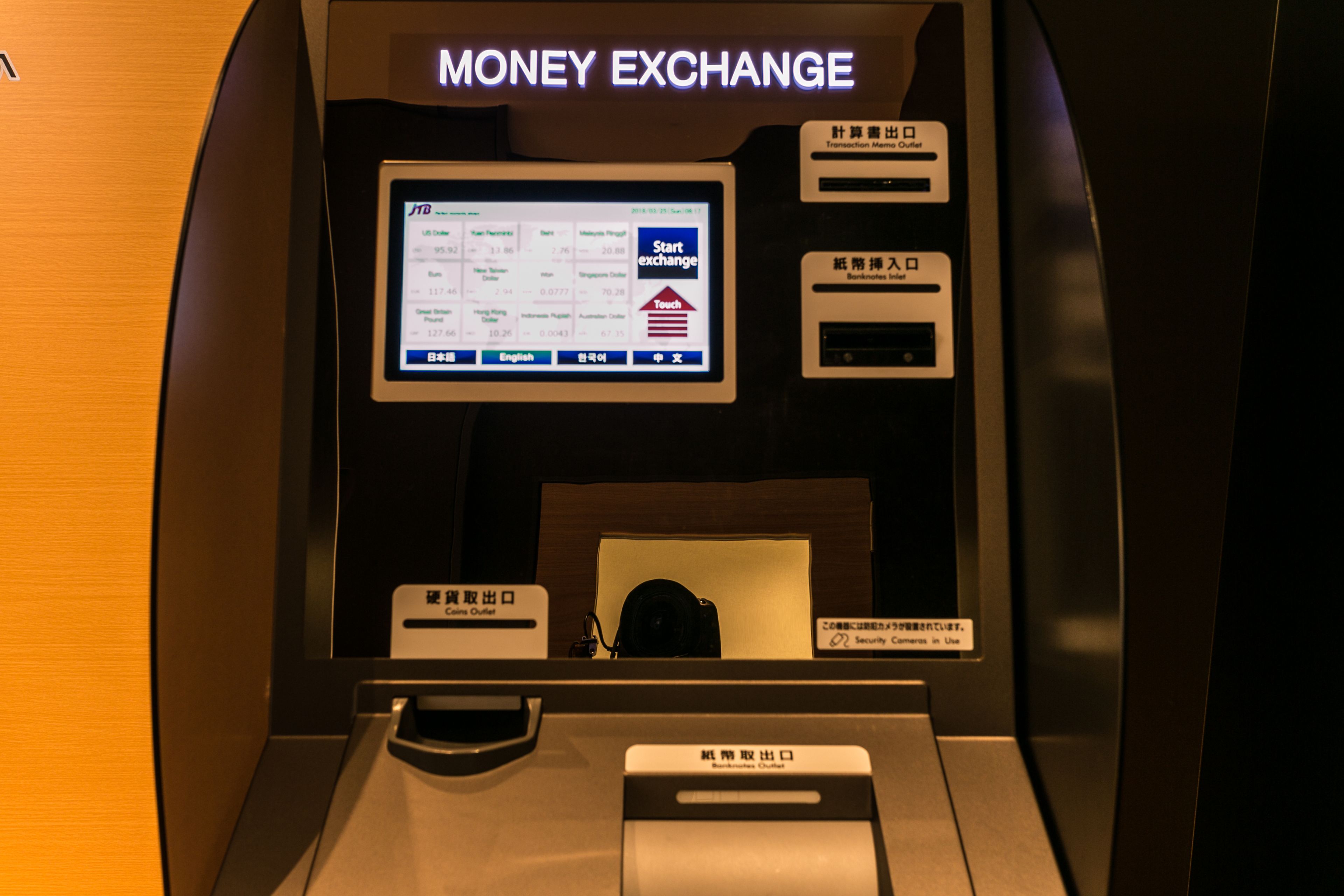 A money exchange machine with a screen displaying exchange rates and a card reader.