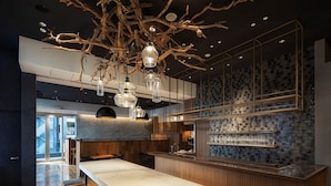 Eine moderne Küche mit einer langen Arbeitsplatte, Hockern und einer außergewöhnlichen Chandelier.