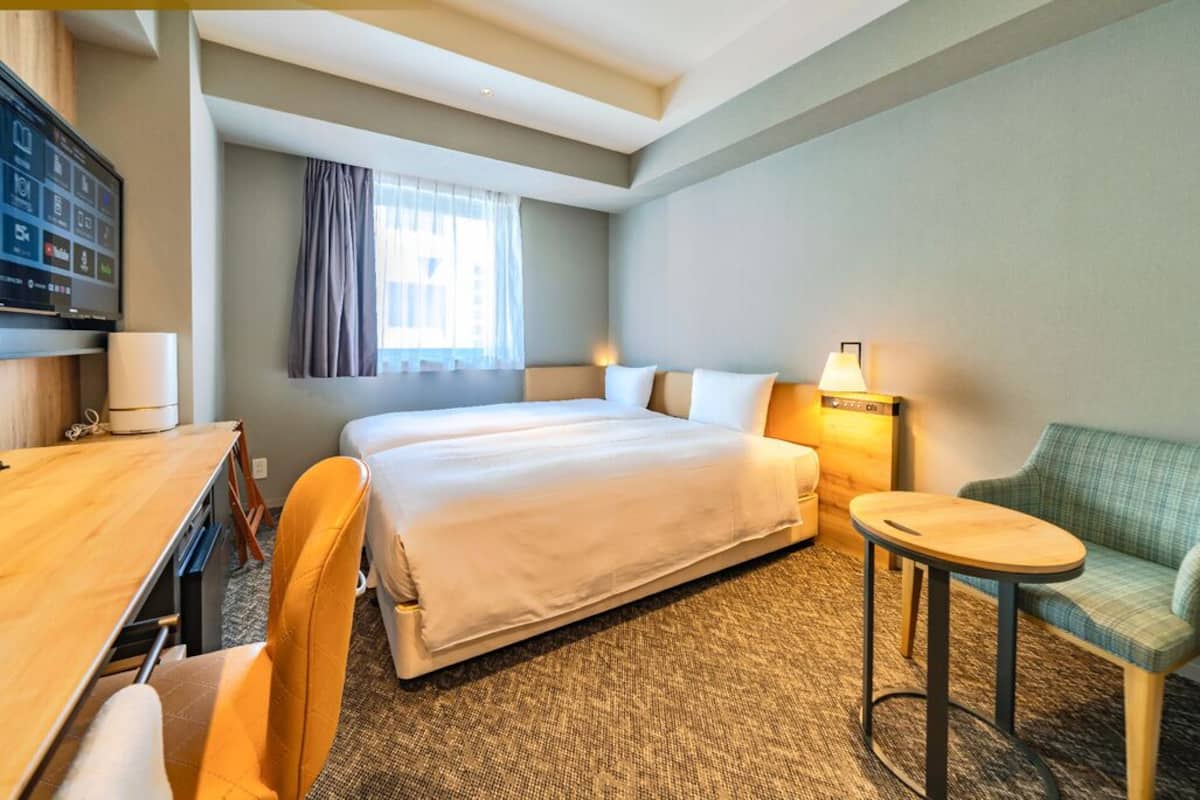 Une chambre d’hôtel comprenant un lit, un bureau, une chaise, une petite table et un téléviseur.