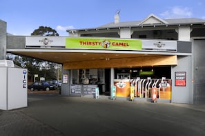 Un ventanilla de autoservicio con un letrero que anuncia 'Thirsty Camel' y 'Asado Dominical'.