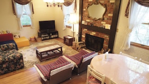 Una sala de estar acogedora con chimenea, televisor y comedor con mesa y sillas.