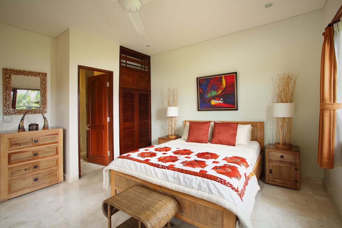 A bedroom with a bed, wooden nightstands, a dresser, and a bench.