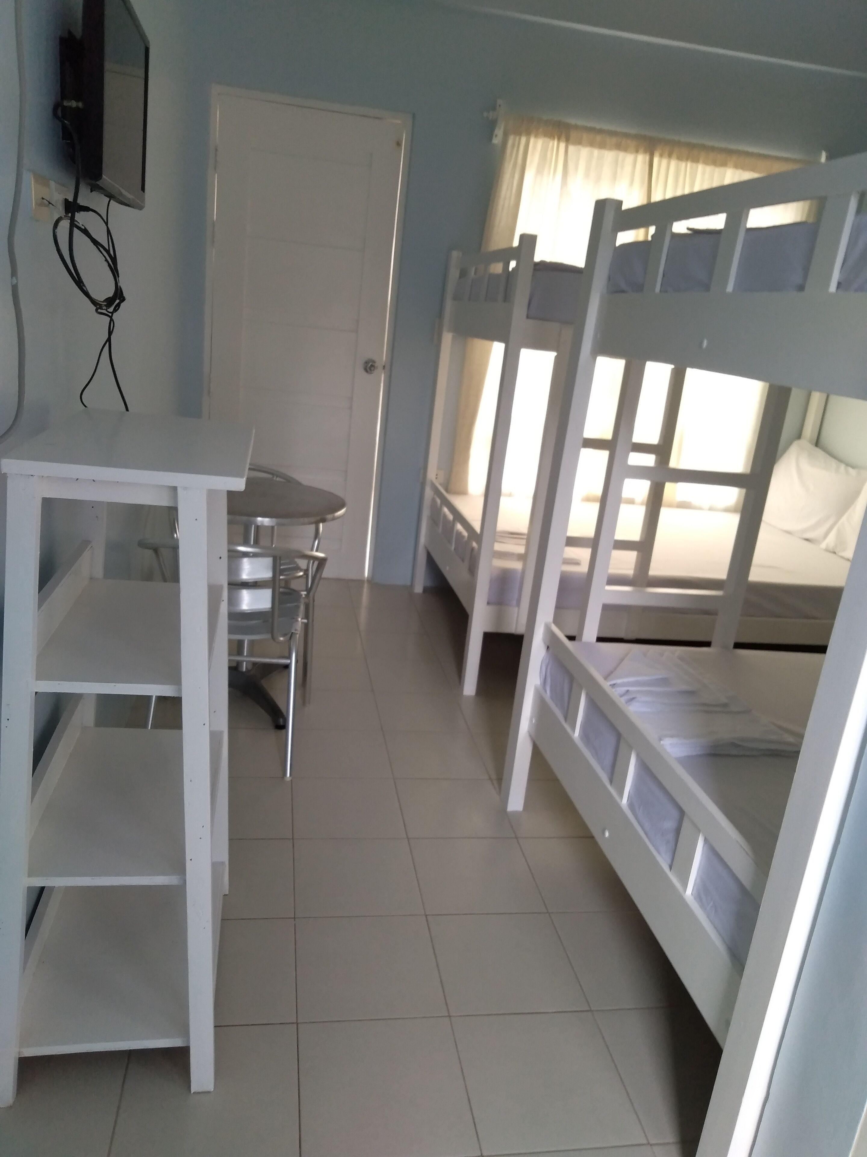A room with bunk beds, a desk, and a chair.