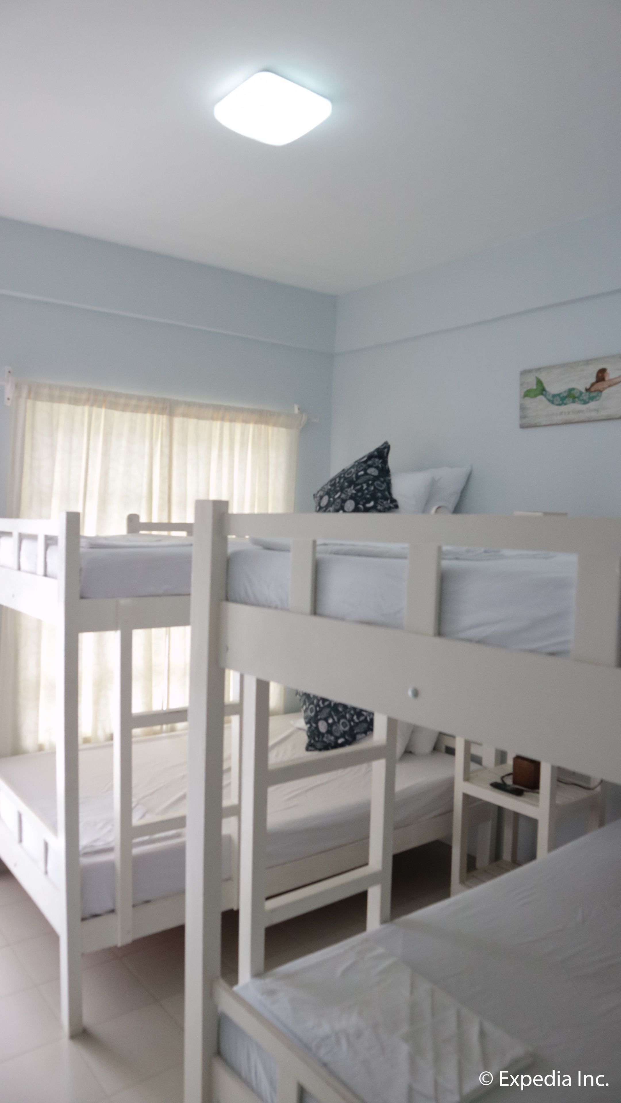 Dormitorio con literas, ventana, luz de techo y un adorno en la pared.