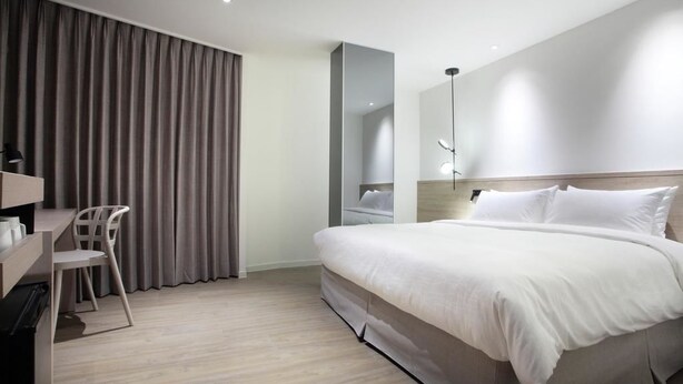 Een moderne hotelkamer met een groot bed, een bureau en een stoel.