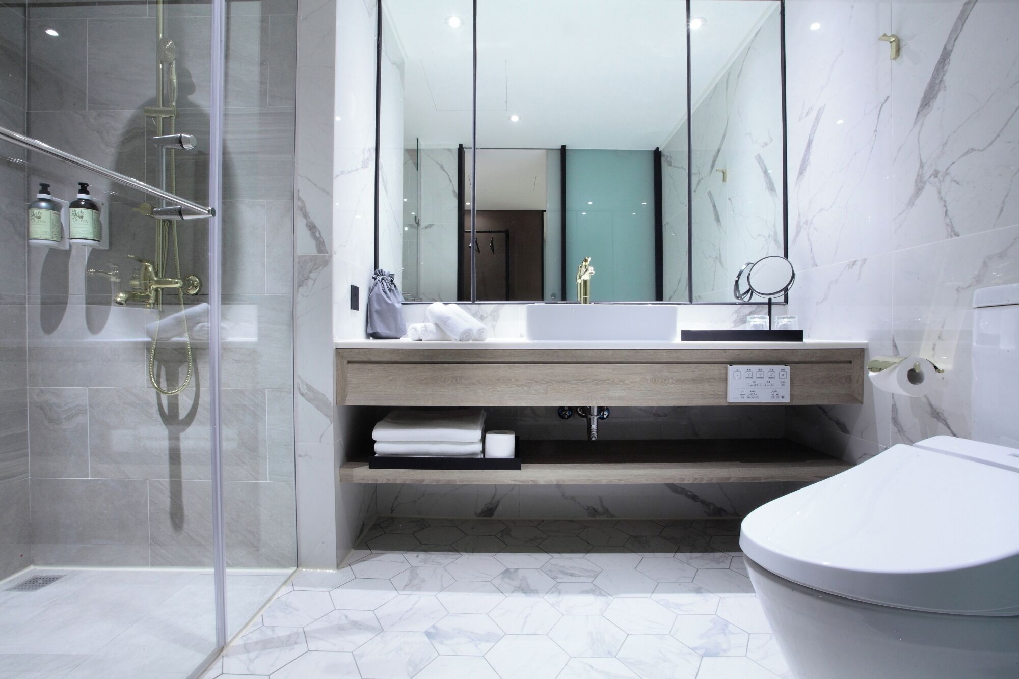 Un baño moderno con cabina de ducha de vidrio, tocador de madera, espejo grande y retrete.