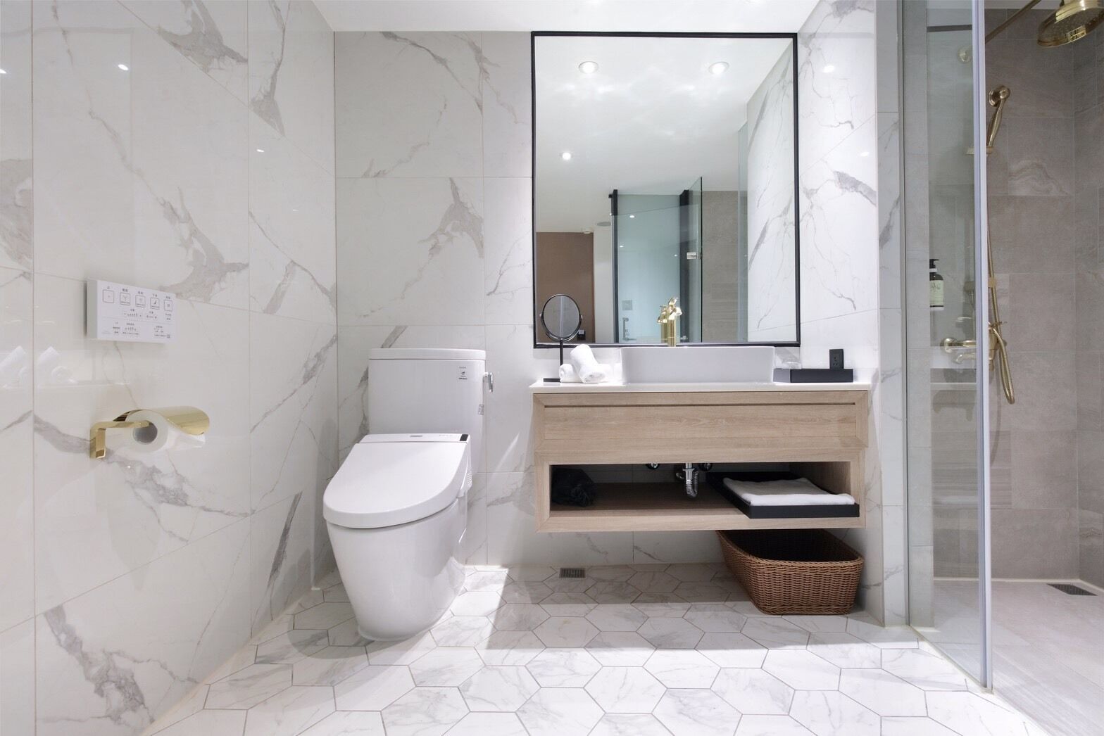Une salle de bain moderne équipée de toilettes, d’un lavabo, d’un miroir et d’une douche.