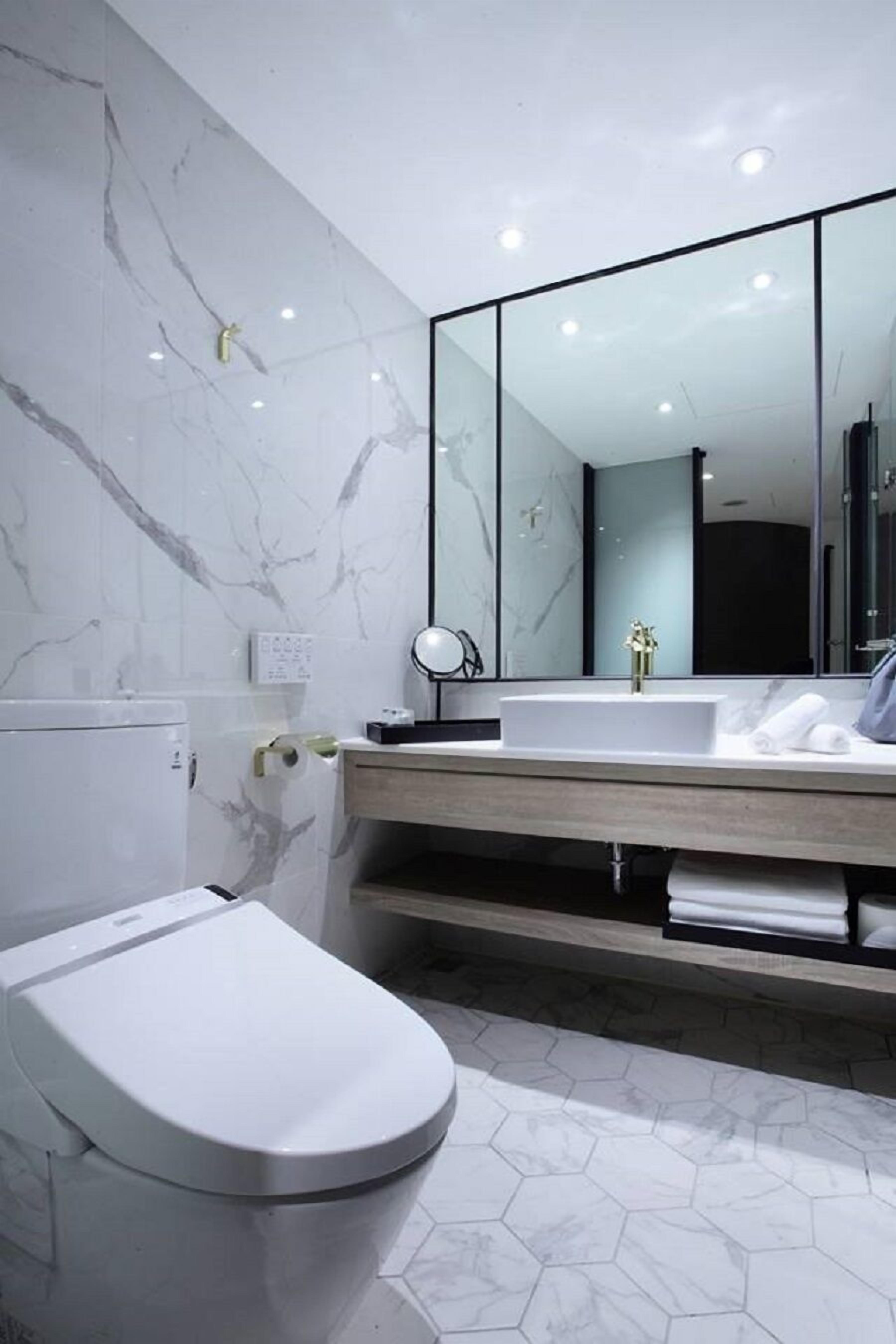 A modern bathroom with a toilet, a sink with a mirror, and a shower area.