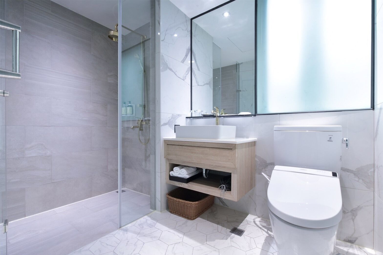 A modern bathroom with a glass shower enclosure, a white toilet, and a vanity with a mirror.