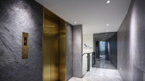 Een moderne lift met een gouden afwerking en een marmeren vloer.