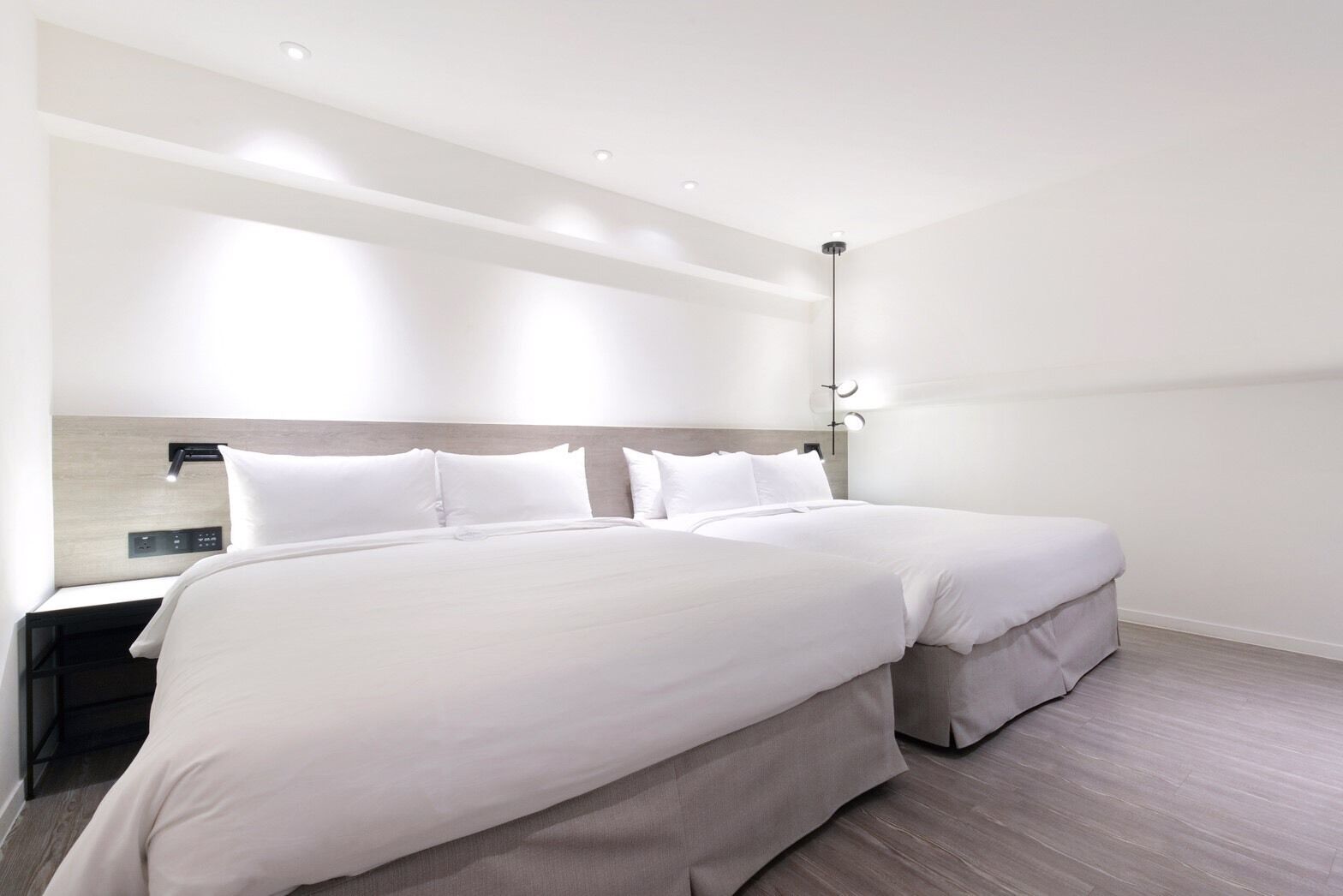 A modern hotel room with a large bed, bedside tables, and a wall-mounted light fixture.