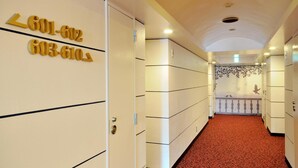 A hotel hallway with numbered doors, a red carpet, and a decorative wall with birds. - Grand Park Hotel Excel Kisarazu (Kisarazu)