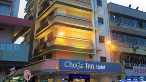 Ett hotell med flera våningar, balkonger och en skylt med texten ”Check Inn Hotel”.