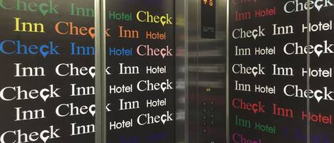 A hotel elevator with walls covered in repeated text saying "Check Inn Hotel Check".