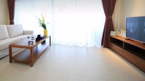 Uma sala de estar com sofá, mesa de centro e televisão de tela plana.