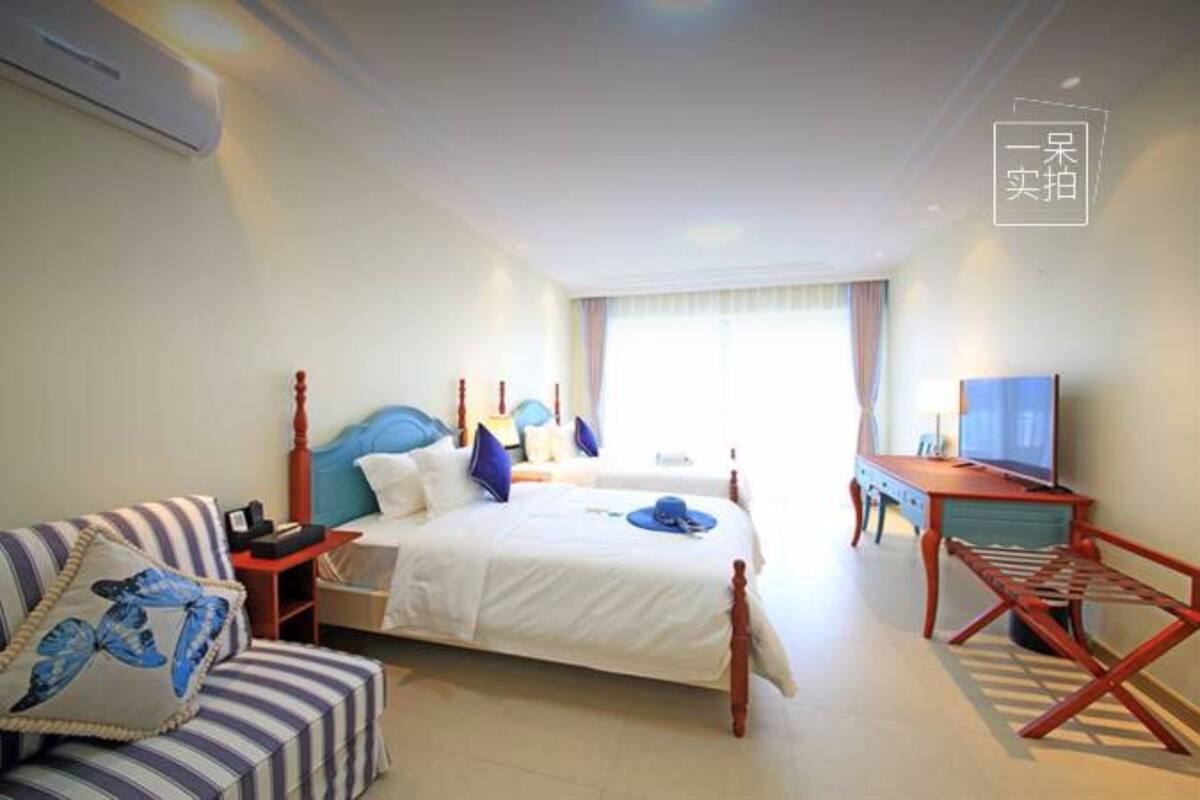 Una habitación de hotel con una cama, televisor, escritorio y una silla.