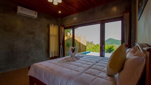 Un dormitorio con una cama grande, techo de madera y vistas a través de un ventanal corredero.