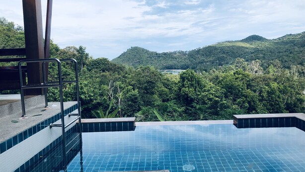Una piscina con vistas a colinas verdes y un cielo despejado.