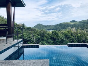 A swimming pool with a view of lush green hills and a clear sky. - Baan View Talay (Ko Pha-ngan)