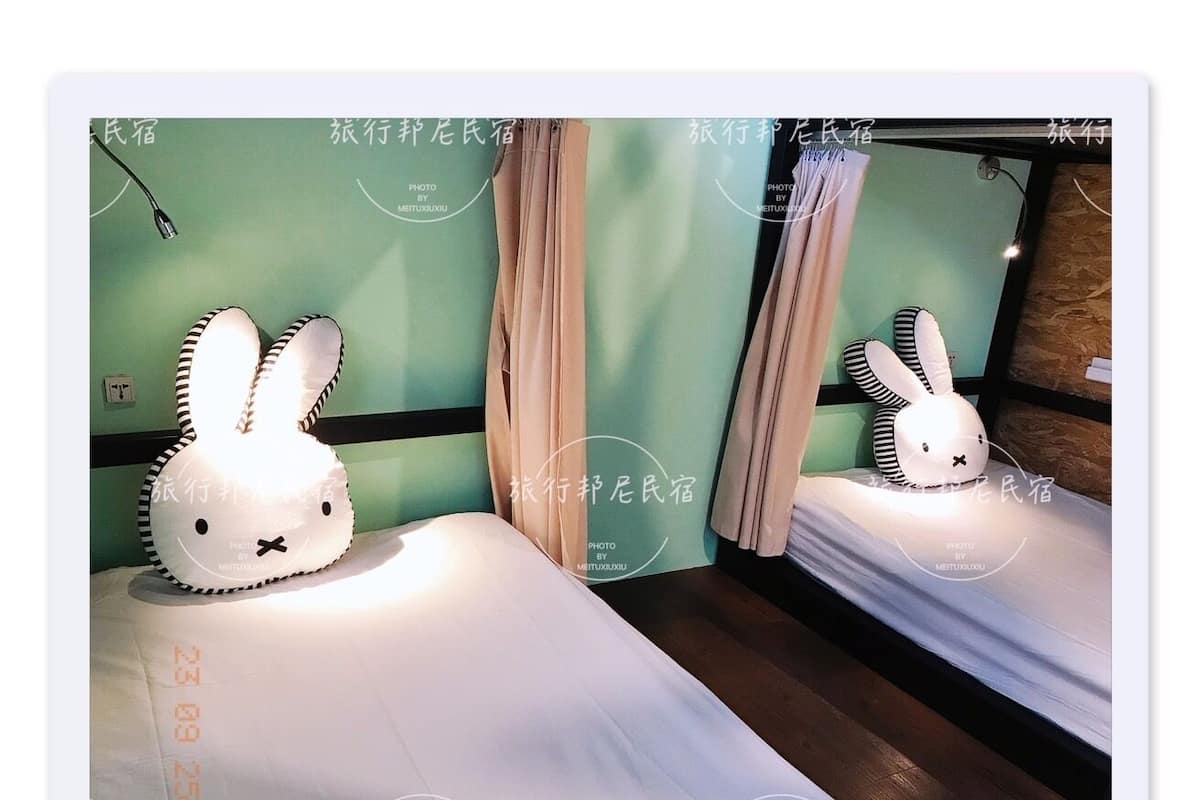 A hotel room with a bed, a pillow with a bunny design, and a mirror reflecting the room.