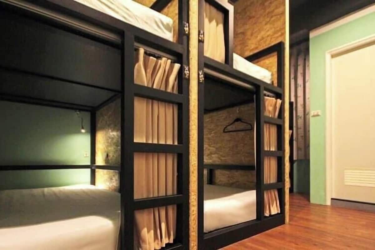 A room with bunk beds, a wooden floor, a door, and a wall with a textured pattern.