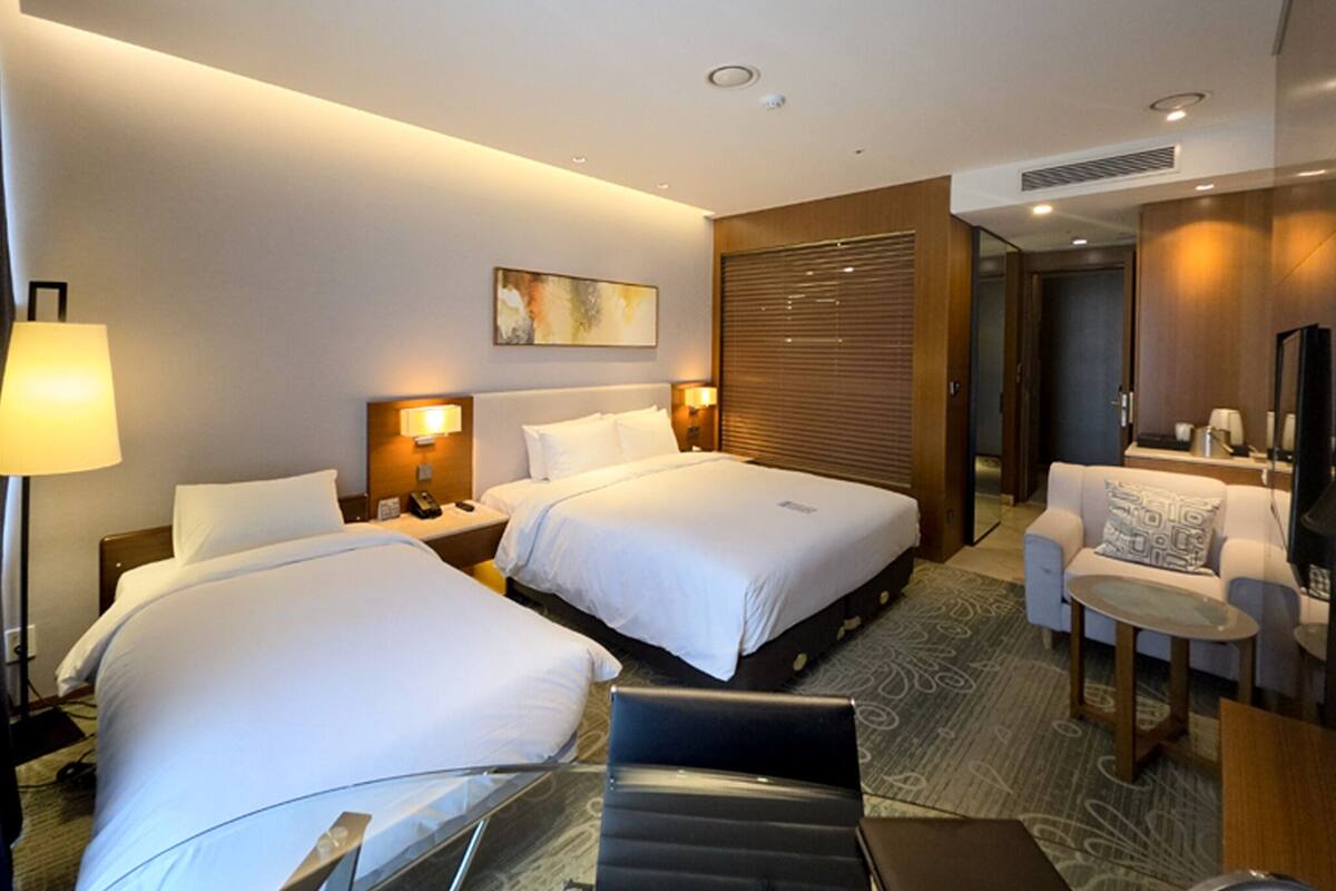 Une chambre d’hôtel avec deux lits, un bureau, une chaise, une télévision et une lampe.