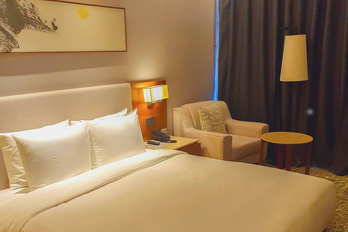 Une chambre d’hôtel avec un grand lit, une chaise, une petite table et une lampe.