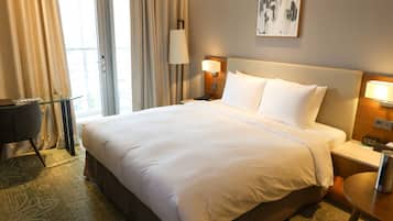 Ein Hotelzimmer mit einem großen Bett, zwei Nachttischlampen, einem Schreibtisch und einem Sessel.