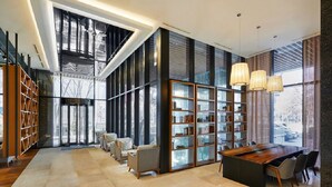 A spacious library with a large wooden table and bookshelves, large windows, and modern lighting. - Skypark Central Seoul Pangyo (Seongnam)