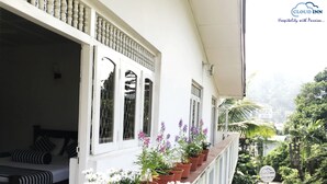 A balcony with potted plants, a bed, and a view of greenery. - Cloud Inn Kandy (Kandy)