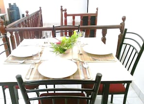 A dining table set with plates, cutlery, and a vase of flowers. - Cloud Inn Kandy (Kandy)