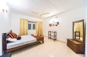 A bedroom with a bed, a ceiling fan, a dresser, a mirror, and a window with curtains. - Cloud Inn Kandy (Kandy)