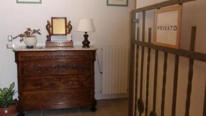 A wooden dresser with a mirror and a lamp, a potted plant, and a 'PRIVATO' sign on a metal gate.