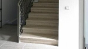 A staircase with a metal railing, a chandelier, and a framed picture on the wall.