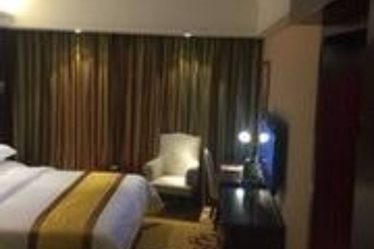 A hotel room with a bed, a chair, a desk, and a curtain.