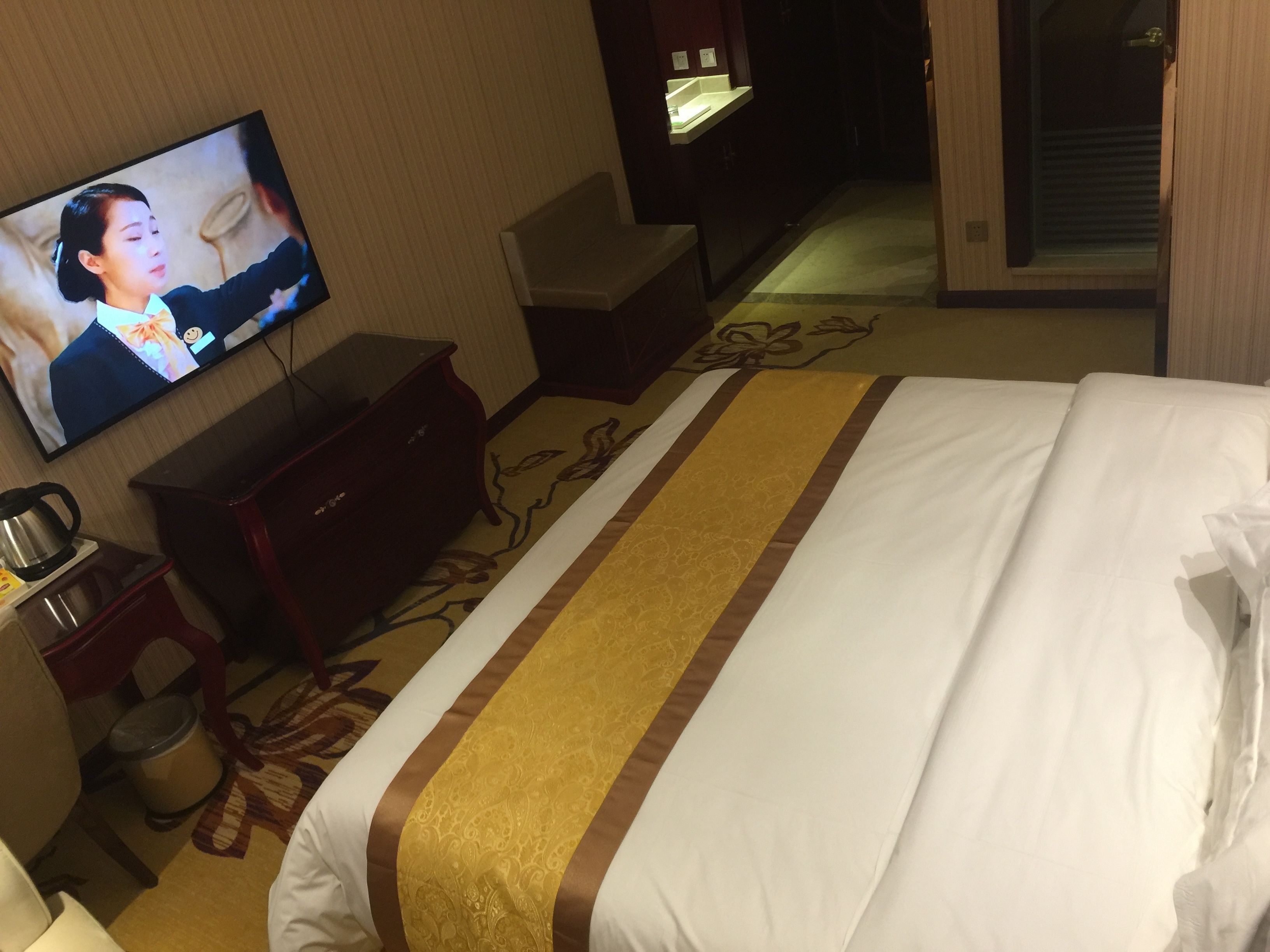 A hotel room with a bed, a television, a dresser, and a coffee maker.
