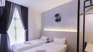 Et hotelværelse med to enkeltsenge, et skrivebord og en stol.