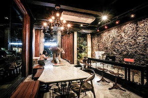 An indoor dining area with a marble table, wooden benches, and ornate wall decorations.