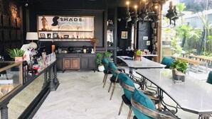 Interior de un restaurante con barra, mesas y un ventanal grande.