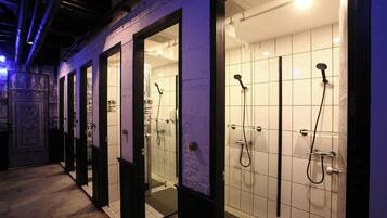 A row of glass-enclosed shower rooms with individual shower heads and a tiled floor.