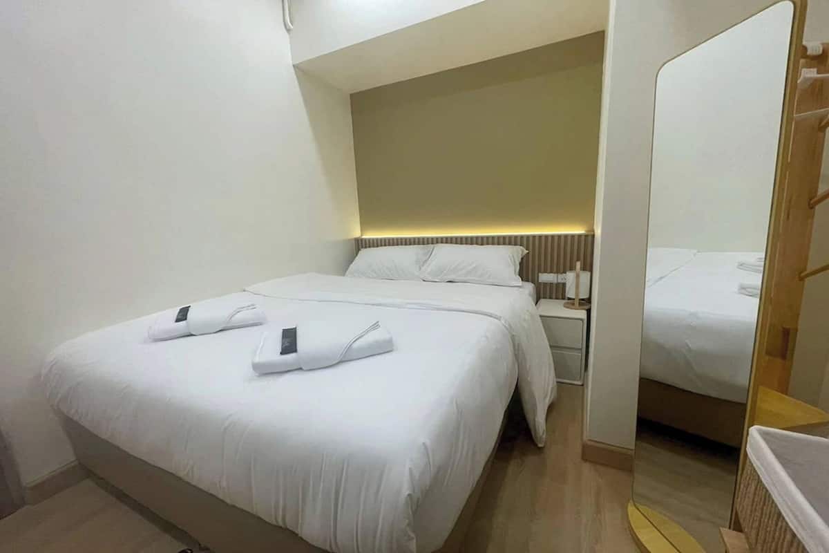 Quarto de hotel com cama, mesa de cabeceira e espelho.