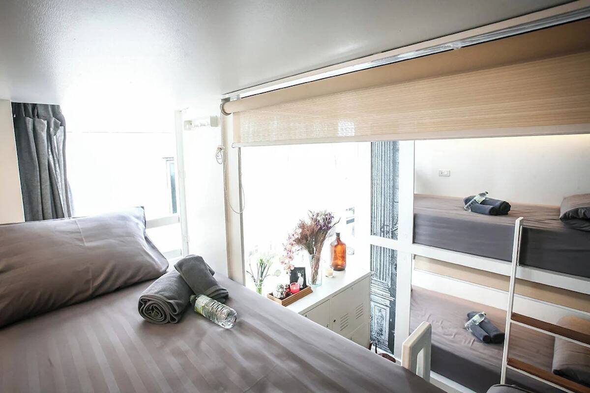 Quarto de hotel com cama, janela e beliche.