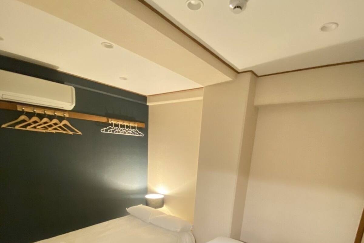 A hotel room with two beds, a wall-mounted air conditioner, and a wall-mounted light fixture.