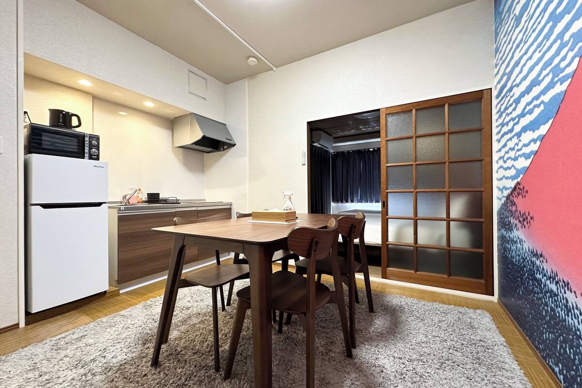 A compact kitchen with a dining area, featuring a microwave, stove, and a large window with a view.